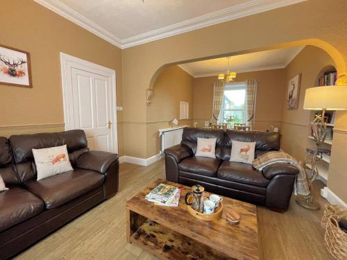 a living room with leather couches and a coffee table at Pass the Keys Beautiful House With Stunning Views Kirkcudbright in Kirkcudbright