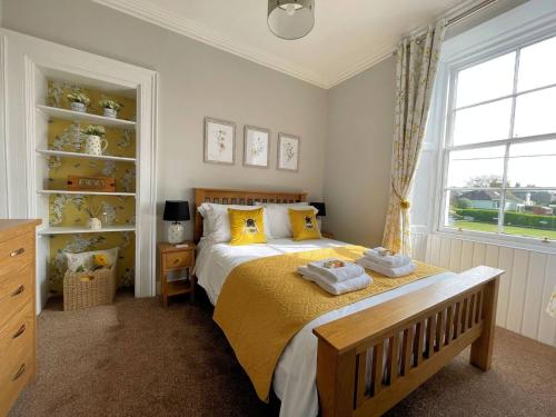 a bedroom with a bed with yellow pillows and a window at Pass the Keys Beautiful House With Stunning Views Kirkcudbright in Kirkcudbright