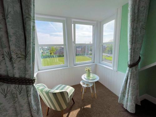 a room with two windows and a chair and a table at Pass the Keys Beautiful House With Stunning Views Kirkcudbright in Kirkcudbright