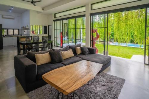 a living room with a couch and a wooden table at Lush 3 BR enclose living room next to Canggu beach in Canggu