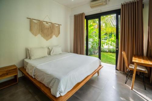 a bedroom with a bed and a desk and a window at Lush 3 BR enclose living room next to Canggu beach in Canggu