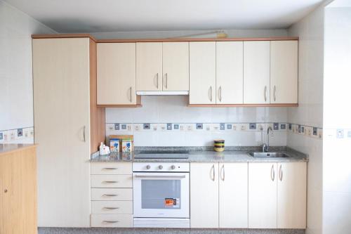 a kitchen with white cabinets and a white oven at Casa San Martiño - Teo in Rua De Francos