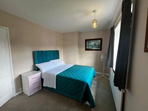 a bedroom with a bed with a blue comforter at Carol Lodge in Morden