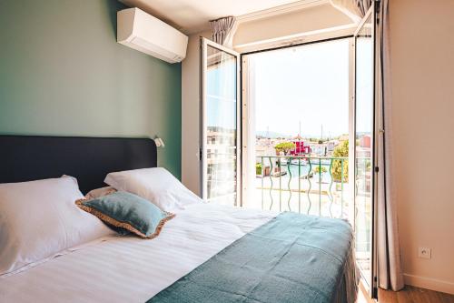 a bedroom with a bed and a large window at Le Suffren Hôtel in Grimaud
