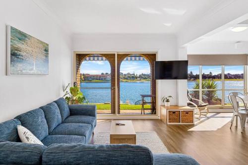 a living room with a blue couch and a large window at Lakeside Mews in Grange