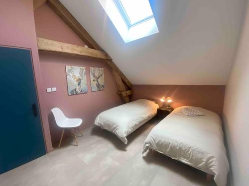 a attic bedroom with two beds and a chair at Villenouan domaine et gites in Lailly-en-Val
