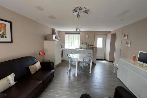 un salon avec un canapé et une table et une cuisine dans l'établissement Maison entre terre & mer, à Pirou