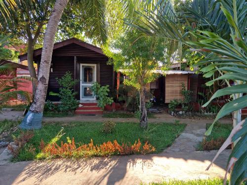 a small house with palm trees in front of it at Bungalow Chez Mouch Nosy Be 7 in Nosy Be