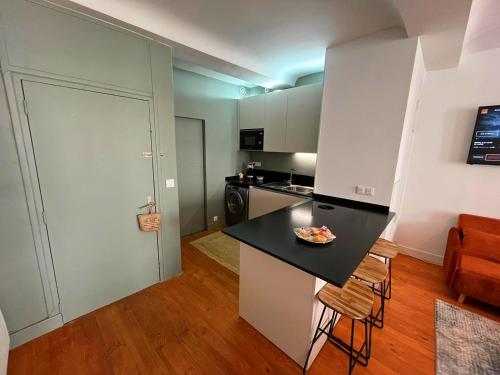 een keuken met een zwart aanrechtblad in een kamer bij Élégant Studio en Hypercentre dans le Quartier Historique Animé avec Parking Gratuit in Caen