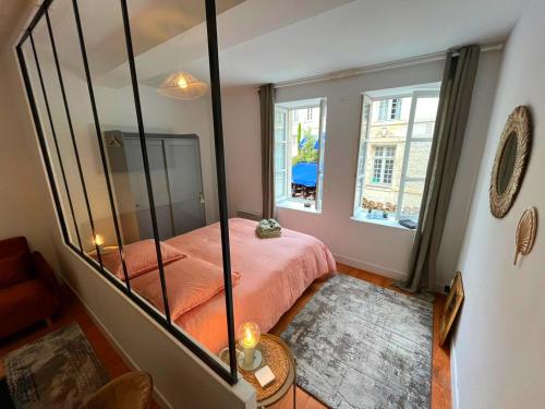 - une chambre avec un lit rose et un miroir dans l'établissement Élégant Studio en Hypercentre dans le Quartier Historique Animé avec Parking Gratuit, à Caen
