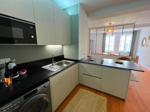 een keuken met een spoelbak en een wasmachine bij Élégant Studio en Hypercentre dans le Quartier Historique Animé avec Parking Gratuit in Caen
