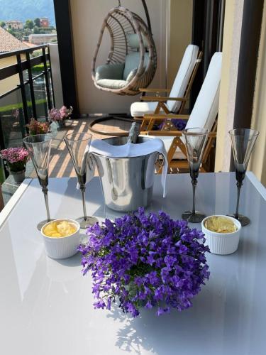 a table with purple flowers and glasses on a balcony at La Rosa del Lago in Lenno
