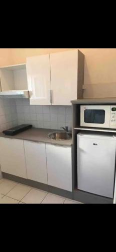 une cuisine avec un évier et un micro-ondes dans l'établissement Appartement port GRUISSAN, à Gruissan
