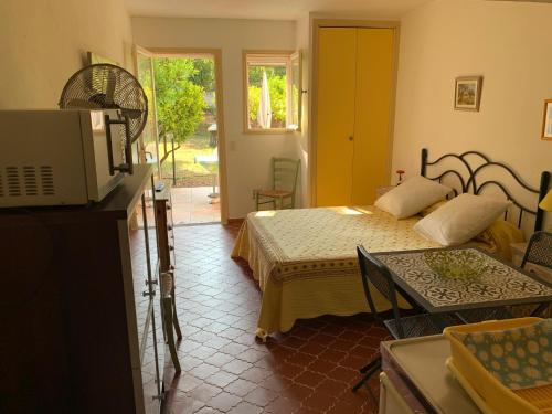 une chambre avec un lit et une télévision dans une pièce dans l'établissement Les Oliviers, à Grimaud