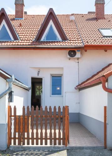 a white house with a wooden fence in front of it at Tokaj Family Apartment in Tokaj