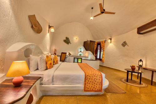 um quarto com uma cama e uma mesa com um candeeiro em The Earth at Ranthambore em Sawai Madhopur