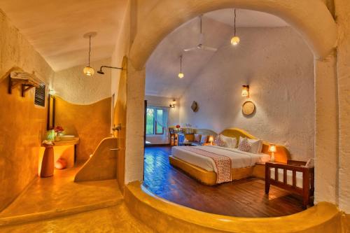 a bedroom with a bed in a room with an archway at The Earth at Ranthambore in Sawāi Mādhopur