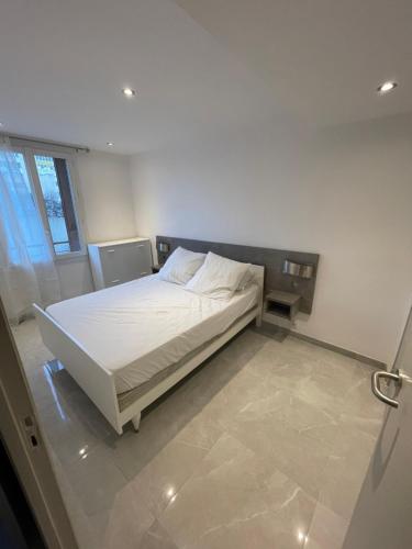 un lit blanc dans une chambre avec une fenêtre dans l'établissement La perle marseillaise, à Marseille