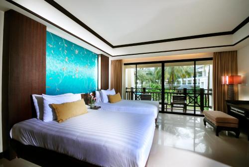 een slaapkamer met 2 bedden en een blauw schilderij aan de muur bij Khaolak Orchid Beach Resort - SHA Extra Plus in Khao Lak