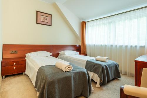 a hotel room with two beds and a window at Hotel Medūna in Druskininkai