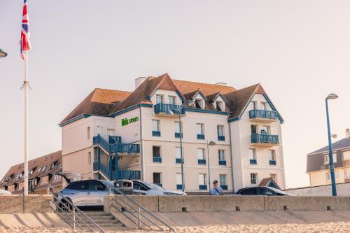 a large white building with cars parked in front of it at ibis Styles Deauville Villers Plage in Villers-sur-Mer