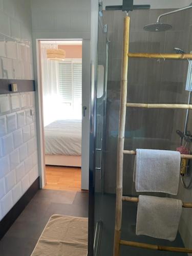 une salle de bain avec une douche avec une serviette et un lit dans l'établissement Les prés salés, à Hautot-sur-Mer