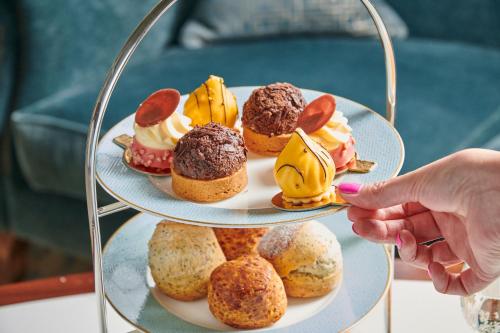 a person holding a plate of pastries on a tray at Matfen Hall Hotel, Golf & Spa in Matfen