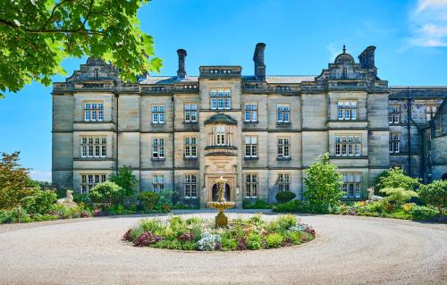 an old mansion with a garden in front of it at Matfen Hall Hotel, Golf & Spa in Matfen