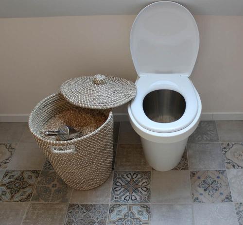 a bathroom with a toilet and a basket at Simples Escales : gîte nature, détente et sauna in Les Rosiers-sur-Loire