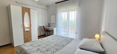 een slaapkamer met een bed, een bureau en een raam bij Apartments Rudolf in Krk