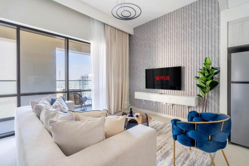 a living room with a white couch and a tv at GuestReady - Lux living with an infinity pool in Dubai