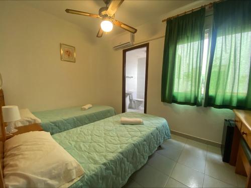 1 dormitorio con 2 camas y una ventana con cortinas verdes en Hotel El Pescador, en Sant Pere Pescador