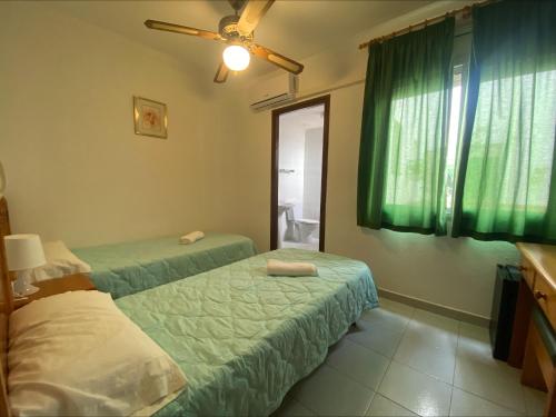 a bedroom with two beds and a window with green curtains at Hotel El Pescador in Sant Pere Pescador