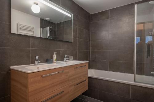 une salle de bain avec un lavabo, un miroir et une baignoire dans l'établissement Cairn Harmony - Apartment B209, aux Gets
