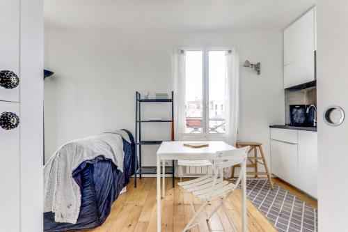 Cette chambre blanche dispose d'un bureau et d'une table. dans l'établissement Appartement lumineux au dernier étage, à Paris