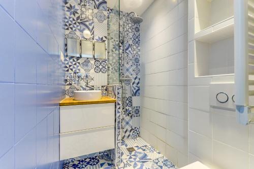 La salle de bains est pourvue de carrelage bleu et blanc et d'un lavabo. dans l'établissement Appartement lumineux au dernier étage, à Paris