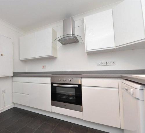 a kitchen with white cabinets and a stove top oven at The Firs - Apartment next to Beach & Forest - Pets are free in Barton on Sea