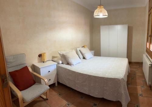 um pequeno quarto com uma cama e uma cadeira em CASA JOAN em Elche