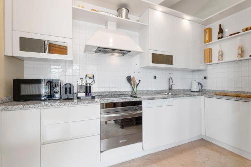 une cuisine blanche avec des armoires blanches et un évier dans l'établissement Penthouse La Bellevue, à Villefranche-sur-Mer