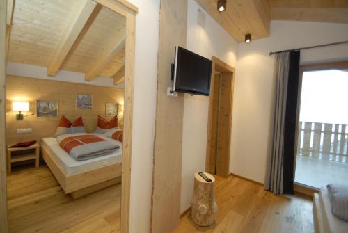 a bedroom with a bed and a flat screen tv at Mühlerhof in Funes