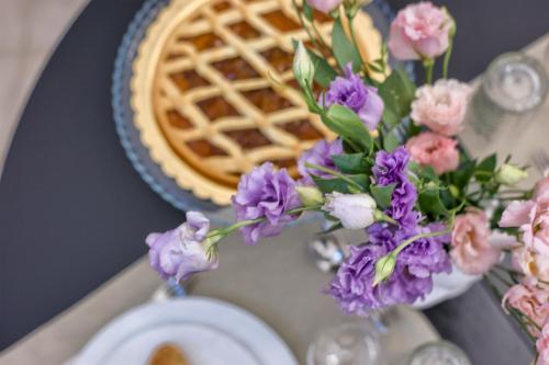 切利诺圣马尔科Villa Neviera Wine Resort & Spa by Cantine Due Palme的桌子上摆着馅饼和紫色的花