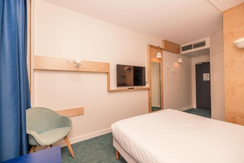a bedroom with a bed and a chair and a tv at ibis Styles Deauville Villers Plage in Villers-sur-Mer