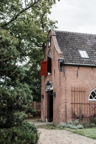 a red brick building with a black roof at Landgoed Huis te Jaarsveld in Jaarsveld