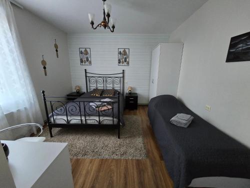 a bedroom with a black bed and a couch at Guest House BENHAUS ar pirti un āra kublu in Sarkaņi