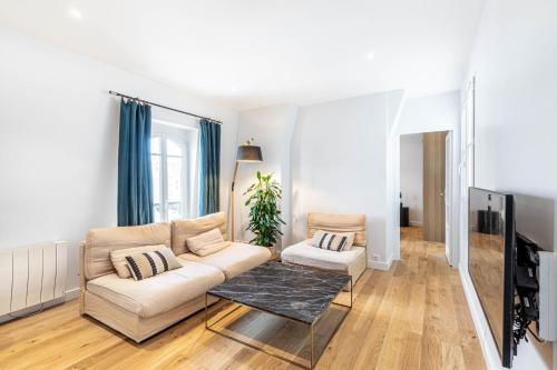 uma sala de estar com um sofá e uma televisão em GuestReady - Your Pied-à-Terre near Princes Park em Paris