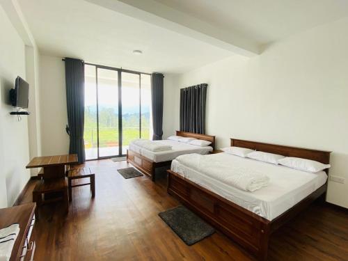a bedroom with two beds and a large window at Kottagala White House in Kotagala