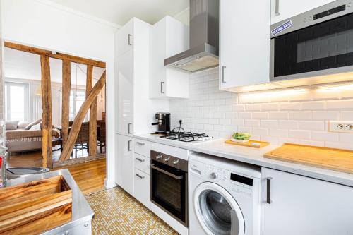 - une cuisine blanche avec lave-linge et sèche-linge dans l'établissement GuestReady - Apt. Lumineux pour 2 près du Marais, à Paris