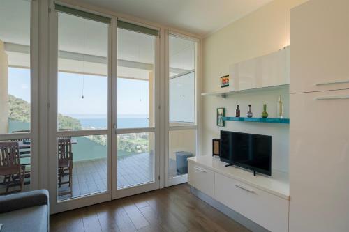a living room with a television and large windows at Moonstone Home - Seaview, Parking, WiFi in Vallecrosia