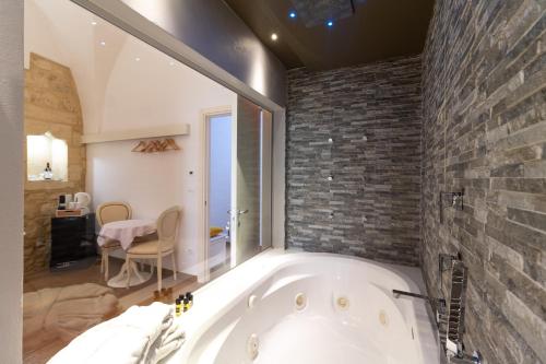 a bath tub in a bathroom with a brick wall at Le Nicchie luxury rooms in Lecce