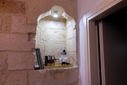 a shelf on a brick wall with a bottle of wine at Le Nicchie luxury rooms in Lecce